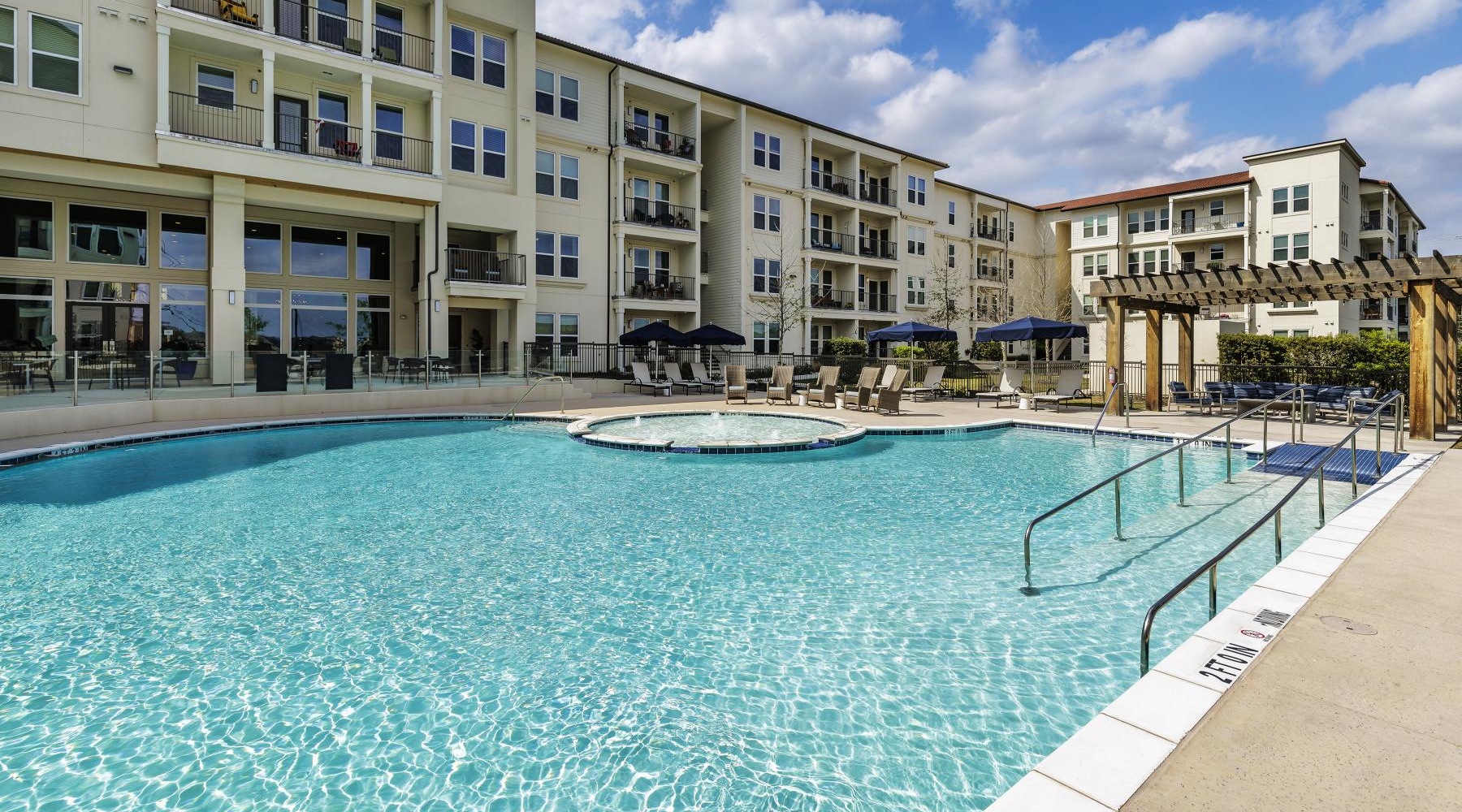 a pool with chairs and umbrellas by a building
