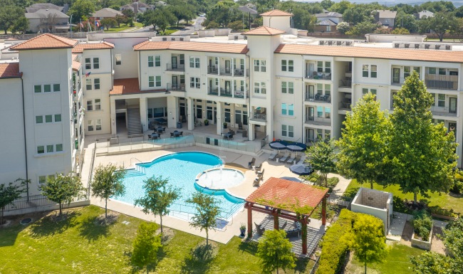 Aerial view of the community garden and pool area at our 55 and over apartments in San Antonio, featuring sunflowers in beds.