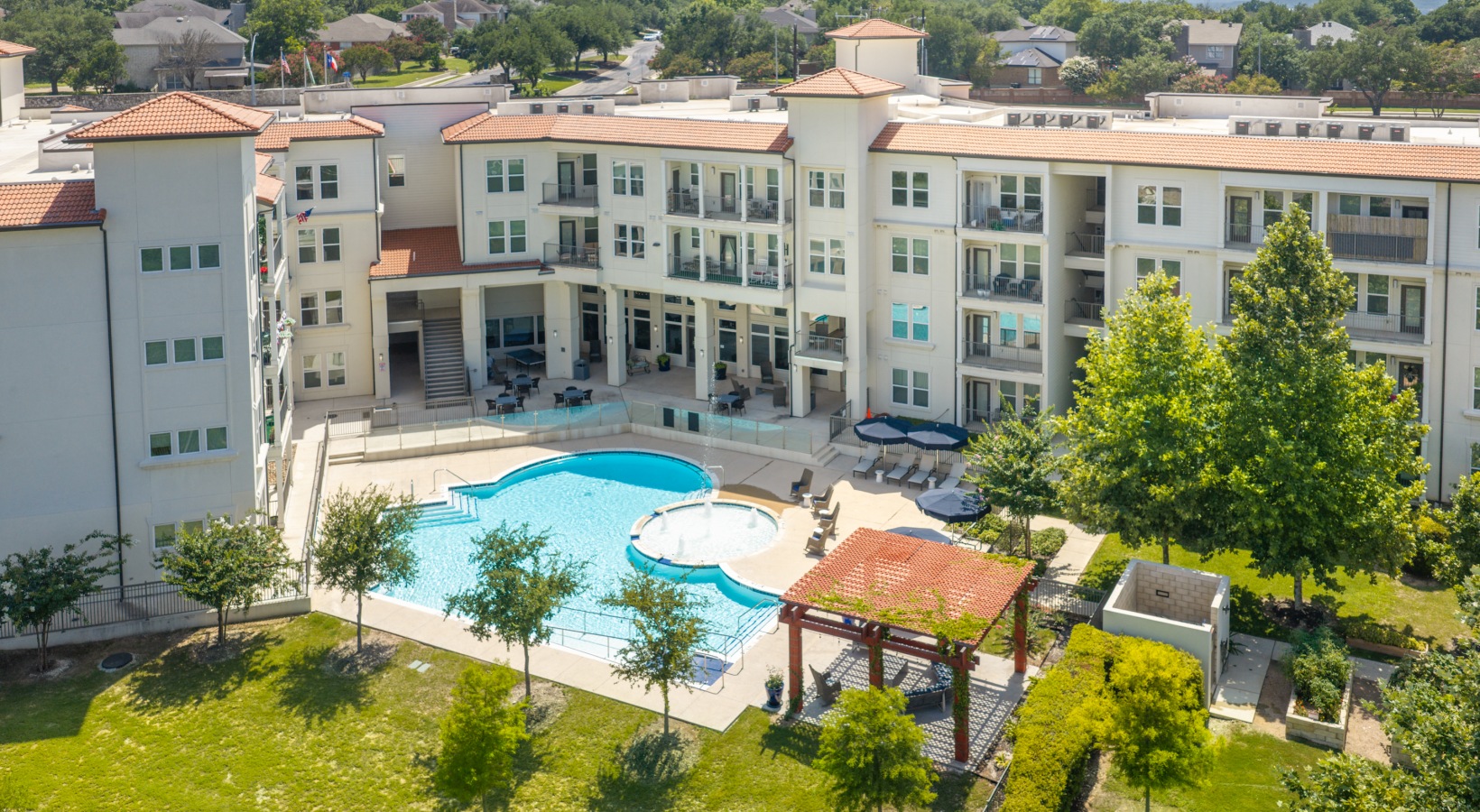 Aerial view of the community garden and pool area at our 55 and over apartments in San Antonio, featuring sunflowers in beds.